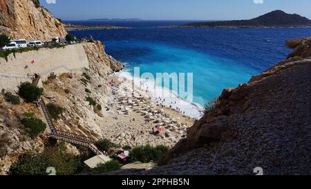 Von der Straße aus hat man einen tollen Blick auf die Menschenmassen, die sich am Strand entspannen. Menschen im Meer schwimmen. Draufsicht auf Kaputas Beach zwischen Kas und Kalkan Stockfoto