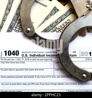 Polizeihandschellen liegen auf der Steuerform 1040. Das Konzept der Probleme mit dem Gesetz nach der Nichtzahlung von Steuern Stockfoto