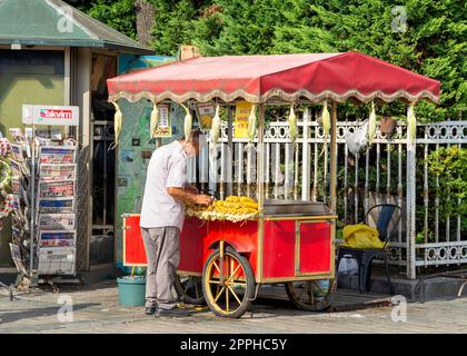 Ein Mann mittleren Alters, der Mais auf einem traditionellen türkischen Fast-Food-Wagen am Sultanahmet Square, Istanbul, Türkei, verkauft Stockfoto