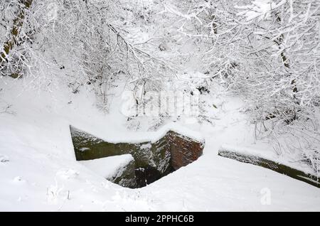 Unterirdischer Bunker alter Backsteinmauern im Winter nach Schneefall Stockfoto