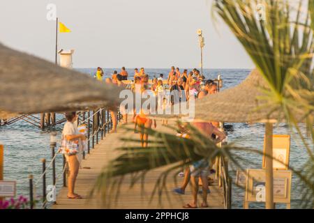 Viele Leute laufen auf einem langen Steg am Meer Stockfoto