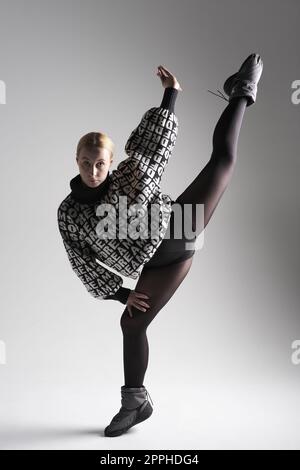 Balletttänzerin in schwarzem Kleid auf grauem Hintergrund, Ballerina posiert und zeigt ihre Flexibilität auf grauem Hintergrund im Studio. Mit Text auf Pullover, VON dem DU TRÄUMST Stockfoto