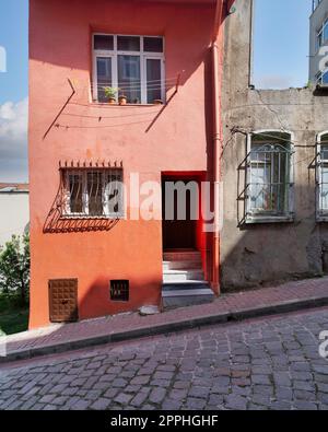 Altes orangefarbenes Haus mit schmiedeeisernen Fenstern, in einer kopfsteingepflasterten Straße, Balat Viertel, Istanbul, Türkei Stockfoto