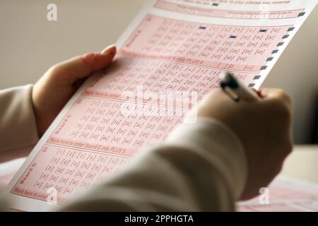 Ein Lotterielos ausfüllen. Eine junge Frau spielt im Lotto und träumt davon, den Jackpot zu gewinnen Stockfoto