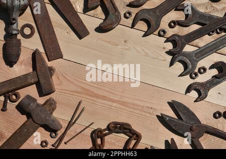 Ein Satz alter und rostiger Werkzeuge liegt auf einem Holztisch in der Werkstatt Stockfoto