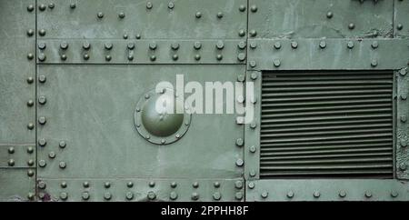 Die Textur der Wand des Tanks, aus Metall und mit einer Vielzahl von Schrauben und Nieten verstärkt. Bilder von der Verkleidung eines Kampffahrzeugs aus dem Zweiten Weltkrieg Stockfoto