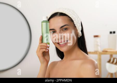 Junge Frau mit einer Flasche Mikellarwasser im Haus Stockfoto