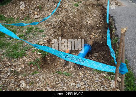 Massefehler, Loch. Blaue Wasserrohre. Reparatur des städtischen Wasserversorgungsnetzes. Die Inschrift auf Serbisch - Achtung, Klempner. Erdarbeiten kommunaler Dienste. Abschreibung und Amortisierung Stockfoto