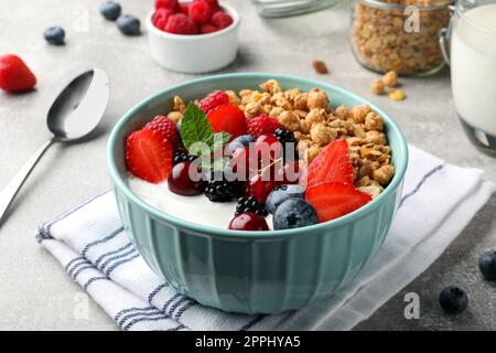 Schüssel mit leckerem Müsli und Beeren auf einem hellgrauen Tisch. Gesundes Essen Stockfoto