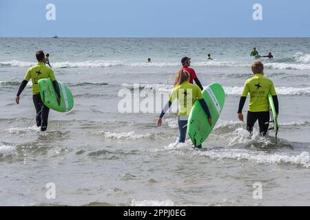 Urlauber nehmen an einer Surfstunde mit einem Lehrer am Fistral Beach in Newquay in Cornwall in Großbritannien Teil. Stockfoto