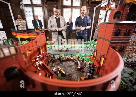 Hanau, Deutschland. 24. April 2023. Boris Rhein (CDU, l), Ministerpräsident von Hessen, und Künstler Oliver Schaffer betrachten ein Diorama von St. Paulus-Kirche in einer Playmobil-Ausstellung zu 175 Jahren Frankfurter St. Paul's Church im Hanau History Museum im Philippsruhe Palace. Die Ausstellung zeigt die Geschichte der deutschen Demokratie in elf Dioramen, die aus Tausenden von Playmobil-Teilen bestehen. Kredit: Sebastian Christoph Gollnow/dpa/Alamy Live News Stockfoto