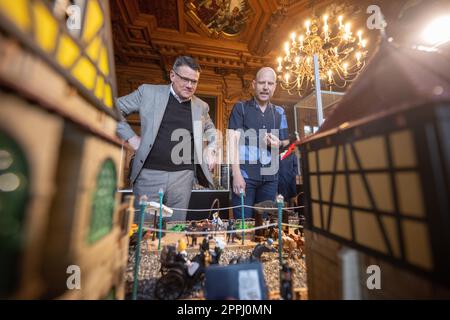 Hanau, Deutschland. 24. April 2023. Boris Rhein (CDU, l), Ministerpräsident von Hessen, und Künstler Oliver Schaffer betrachten ein Diorama in einer Playmobil-Ausstellung über 175 Jahre Frankfurter Paulskirche im Hanau History Museum in der Burg Philippsruhe. Die Ausstellung zeigt die Geschichte der deutschen Demokratie in elf Dioramen, die aus Tausenden von Playmobil-Teilen bestehen. Kredit: Sebastian Christoph Gollnow/dpa/Alamy Live News Stockfoto