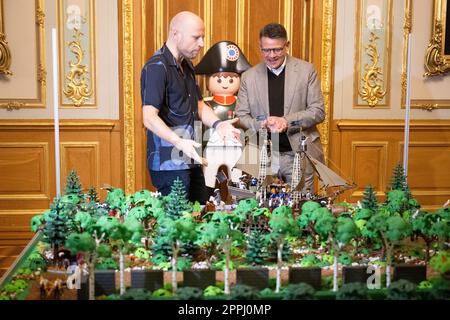 Hanau, Deutschland. 24. April 2023. Boris Rhein (CDU, r), Ministerpräsident von Hessen, spricht mit dem Künstler Oliver Schaffer auf einer Playmobil-Ausstellung über 175 Jahre Frankfurter Paulskirche im Hanau History Museum in der Burg Philippsruhe. Die Ausstellung zeigt die Geschichte der deutschen Demokratie in elf Dioramen, die aus Tausenden von Playmobil-Teilen bestehen. Kredit: Sebastian Christoph Gollnow/dpa/Alamy Live News Stockfoto