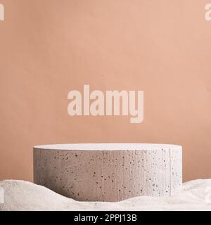 Leeres rundes Betonplattformpodium auf Strandsand und beigefarbenem Hintergrund. Minimaler kreativer Hintergrund für die Präsentation von Kosmetika oder Produkten. Vorderansicht Stockfoto