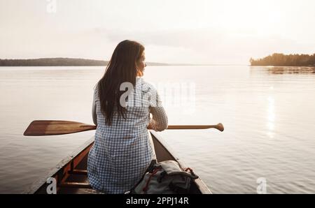 Sie geht aufs Wasser, wann immer sie kann. Rückansicht einer jungen Frau, die eine Kanufahrt auf dem See genießt. Stockfoto