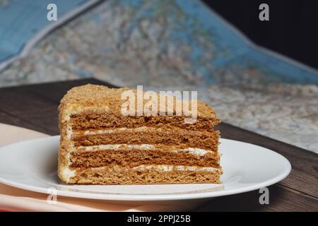 Ein Stück Honigkuchen auf dem Teller neben der Karte auf dem Tisch. Stockfoto