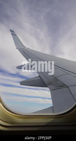 Flügel eines Flugzeuges, Ansicht des Passagiers. Blick durch das Fenster eines Flugzeugs auf seinen glänzenden Flügel Stockfoto