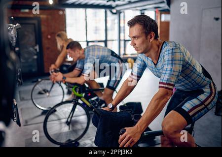 Mann, der auf dem Fahrrad-Trainer im Sportclub Fahrrad fährt Stockfoto