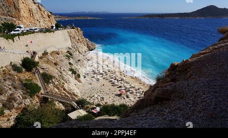 Von der Straße aus hat man einen tollen Blick auf die Menschenmassen, die sich am Strand entspannen. Menschen im Meer schwimmen. Draufsicht auf Kaputas Beach zwischen Kas und Kalkan Stockfoto