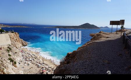 Von der Straße aus hat man einen tollen Blick auf die Menschenmassen, die sich am Strand entspannen. Menschen im Meer schwimmen. Draufsicht auf Kaputas Beach zwischen Kas und Kalkan Stockfoto