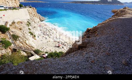 Von der Straße aus hat man einen tollen Blick auf die Menschenmassen, die sich am Strand entspannen. Menschen im Meer schwimmen. Draufsicht auf Kaputas Beach zwischen Kas und Kalkan Stockfoto