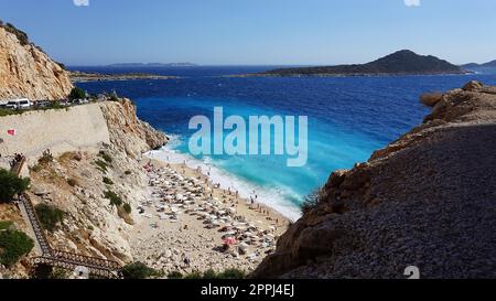 Von der Straße aus hat man einen tollen Blick auf die Menschenmassen, die sich am Strand entspannen. Menschen im Meer schwimmen. Draufsicht auf Kaputas Beach zwischen Kas und Kalkan Stockfoto