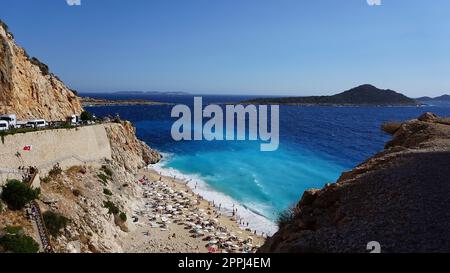 Von der Straße aus hat man einen tollen Blick auf die Menschenmassen, die sich am Strand entspannen. Menschen im Meer schwimmen. Draufsicht auf Kaputas Beach zwischen Kas und Kalkan Stockfoto