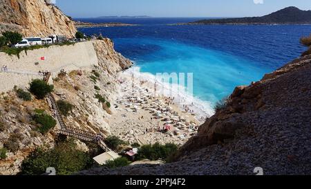 Von der Straße aus hat man einen tollen Blick auf die Menschenmassen, die sich am Strand entspannen. Menschen im Meer schwimmen. Draufsicht auf Kaputas Beach zwischen Kas und Kalkan Stockfoto