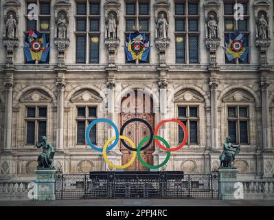 Schließen Sie den Eingang zum Rathaus von Paris. Blick auf die wunderschöne kunstvoll verzierte Fassade des historischen Gebäudes und die olympischen Spiele-Ringe vor den zentralen Türen, die Frankreich 2024 ausrichtete Stockfoto