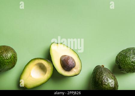 Haas Avocados auf grünem Hintergrund, Draufsicht, Kopierbereich. Gesunde frische organische Avocado-Nahaufnahme. Stockfoto
