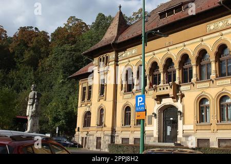 Brasov, Rumänien - 26. September 2022: George Baritiu County Library und ihre Statue vor der Bibliothek. Stockfoto