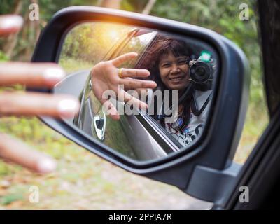 Eine Frau hält eine Digitalkamera in der Hand und macht ein Bild von sich selbst, das im Spiegel reflektiert wird. Stockfoto