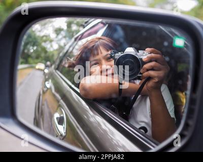 Eine Frau hält eine Digitalkamera in der Hand und macht ein Bild von sich selbst, das im Spiegel reflektiert wird. Stockfoto