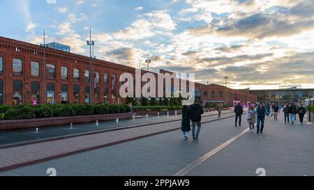 Lodz, Polen - 29. September 2022: Besucher besuchen den inneren Platz von Manufaktura bei Sonnenuntergang, ein Kunstzentrum, ein Einkaufszentrum und einen Freizeitkomplex Stockfoto