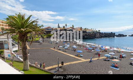 Puerto de Santiago, Teneriffa, Spanien - 20. September 2022: Sonnenbaden am berühmten vulkanischen Strand. Der Strand ist einer der saubersten auf der Insel, Stockfoto