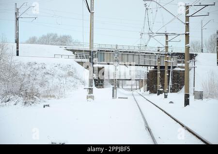 Winterliche Eisenbahnlandschaft, Bahngleise im schneebedeckten Industrieland Stockfoto