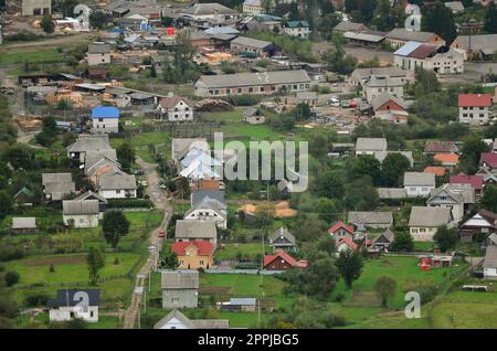 Eine wunderschöne Aussicht auf das Dorf Mezhgorye, Karpaten Region. Eine Menge von Wohngebäuden durch hohe Wald Berge und lange Fluss umgeben Stockfoto