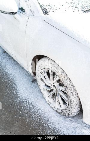 Handwäsche mit Hochdruckwasser in einer Autowaschanlage im Freien. Das Auto ist voller Schaum. Das Konzept der Handwäsche, Selbstbedienung. Stockfoto