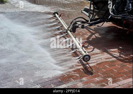 Eine spezielle Maschine wäscht Stadtwege und Straßen mit Wasser Stockfoto