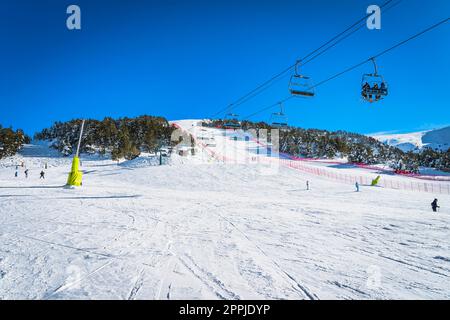 Leute, die mit einem Sessellift fahren und Ski fahren und Snowboarden auf der Skipiste, Andorra Stockfoto