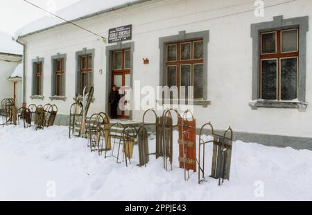 Sirnea, Brasov County, Rumänien, ca. 2000. Kinderschlitten vor dem örtlichen Schulgebäude. Stockfoto