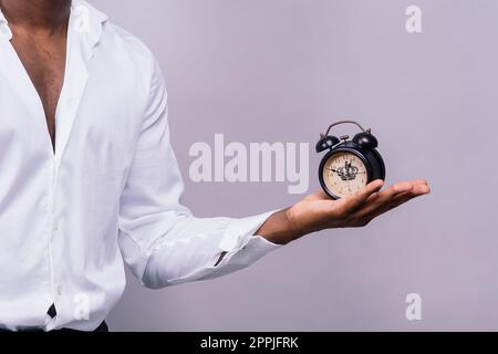 Zeitmanagementkonzept. Schockierter Schwarzer, der die Wanduhr in der Hand hält, läuft die Zeit davon. Stockfoto