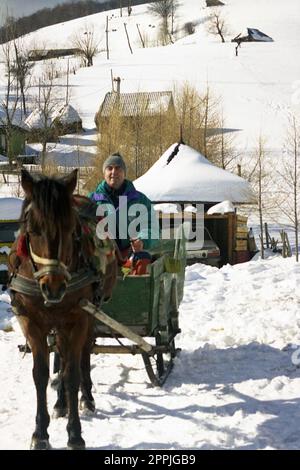 Sirnea, Brasov County, Rumänien, ca. 2000. Ein Mann, der einen traditionellen Pferdeschlitten fährt. Stockfoto