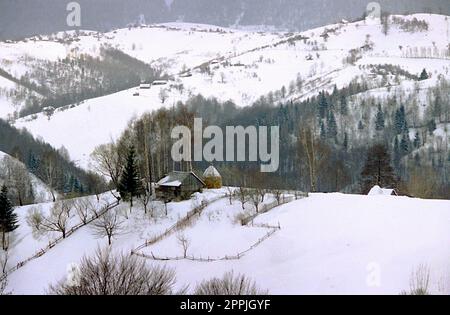 Brasov County, Rumänien, ca. 1999. Winterlandschaft in den Bergen. Abgelegene, eingezäunte landwirtschaftliche Grundstücke. Stockfoto