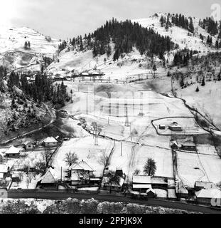 Arges County, Sozialistische Republik Rumänien, ca. 1975. Winterlandschaft in einer Bergregion mit Häusern am Fluss. Stockfoto