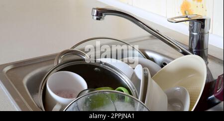 Schmutziges Geschirr und ungewaschene Küchengeräte füllten das Spülbecken Stockfoto