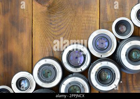 Mehrere Fotolinsen liegen auf braunem Holzhintergrund. Platz für Text Stockfoto