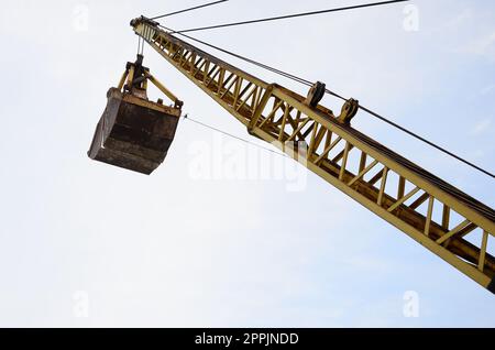 Alte gelbe mechanische Greifvorrichtung auf blauem Himmelshintergrund Stockfoto