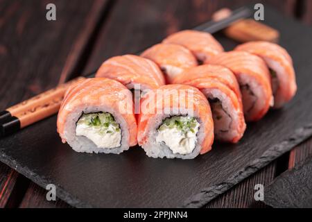 Sushi Roll philadelphia mit Thunfisch und Gurke und Frischkäse auf schwarzem Hintergrund. Sushi-Menü. Japanisches Speisekonzept Stockfoto