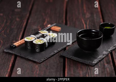 Maki Sushi-Brötchen mit Gurke und Sesam mit Essstäbchen. Sushi-Menü. Japanisches Essen. Stockfoto